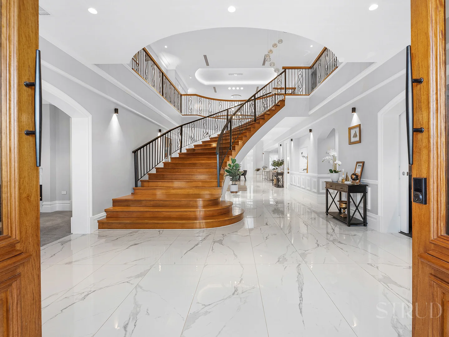 Custom Curved Staircase Brisbane Grand curved timber staircase with wrought iron balustrade in marble foyer